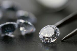 Diamante y pinzas de joyero, diamantes de fondo borrosos, fondo gris, alta calidad, joyería.